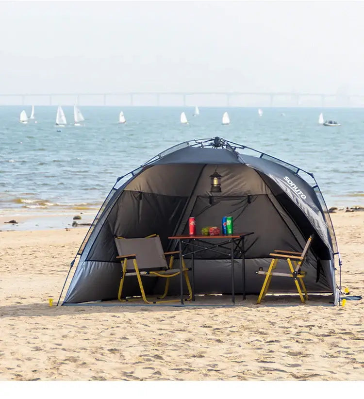 Outdoor one-touch camping tent set up on the beach with a table and chairs, perfect for family picnics and shade.