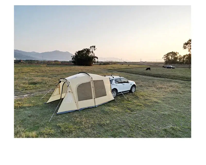 Trunk camping tent set up beside a Tesla in an open field during sunset, showcasing outdoor adventure and portability.