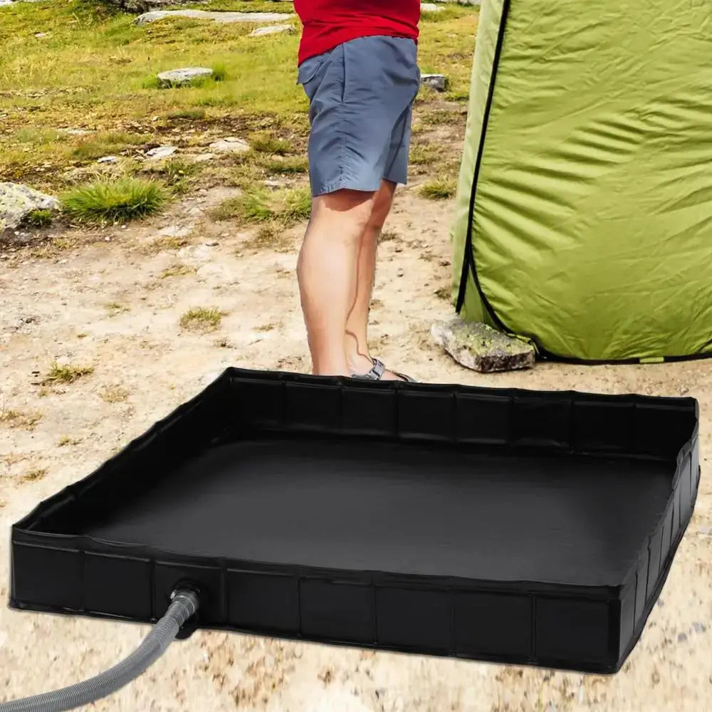 Portable black camping shower floor base next to a tent, ideal for keeping feet clean outdoors.