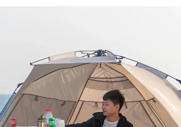 Man enjoying refreshments inside a one-touch camping tent on the beach, perfect for family outings and picnics.