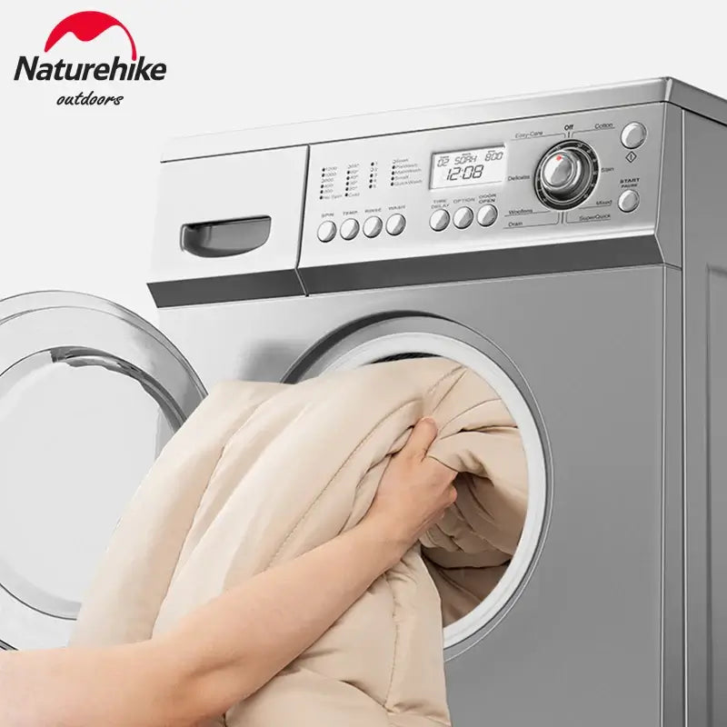 Woman placing Naturehike camping sleeping bag into washing machine for cleaning and maintenance.