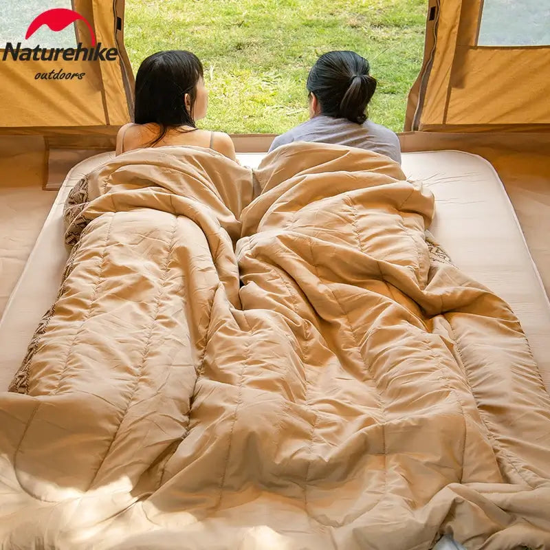 Naturehike ultralight cotton sleeping bag shown with two people relaxing in a tent during outdoor camping.