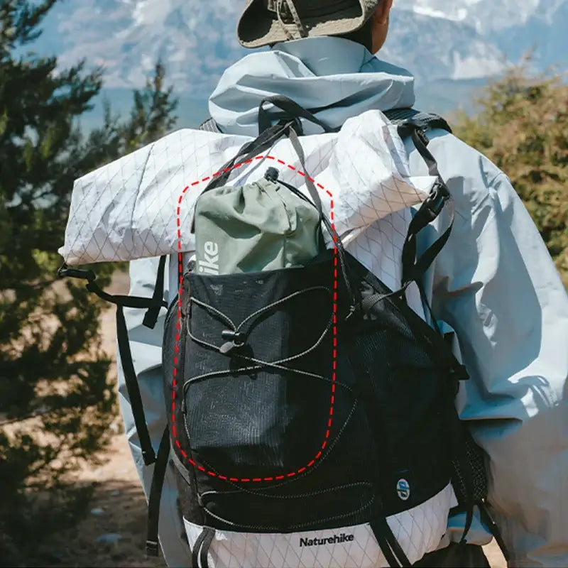 Naturehike backpack with green storage bag, ideal for camping and outdoor adventures, showcased in a scenic environment.